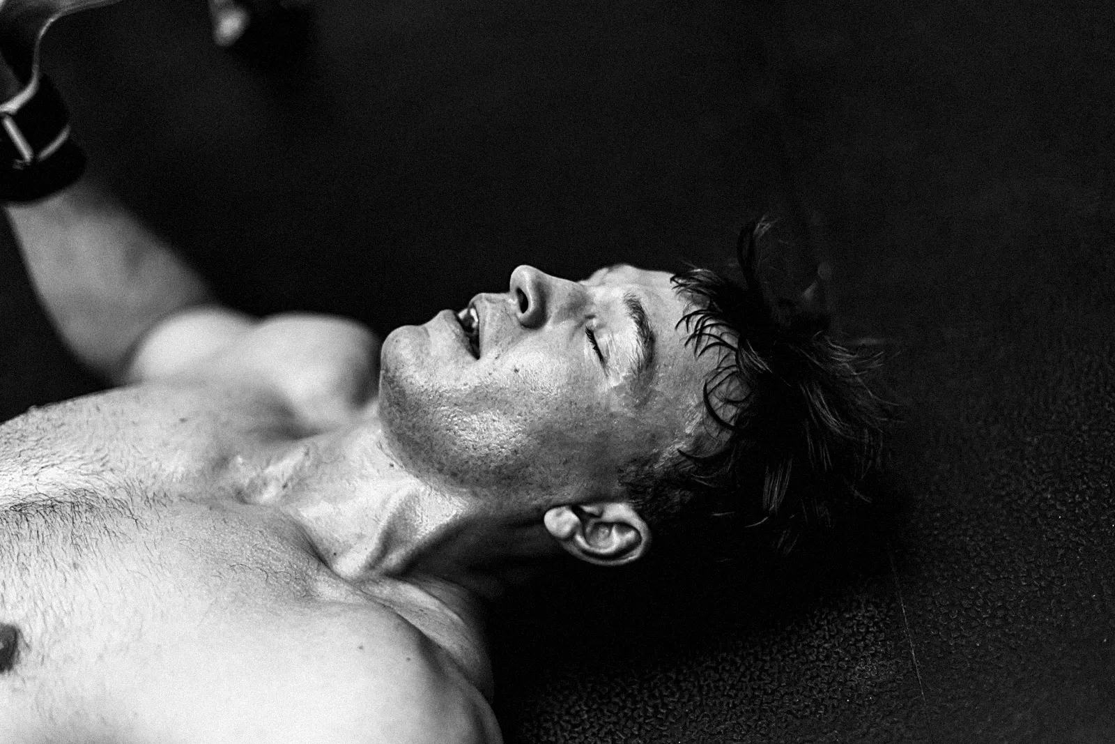 Athlete flat on the floor, drenched in sweat, eyes closed after the final rep
